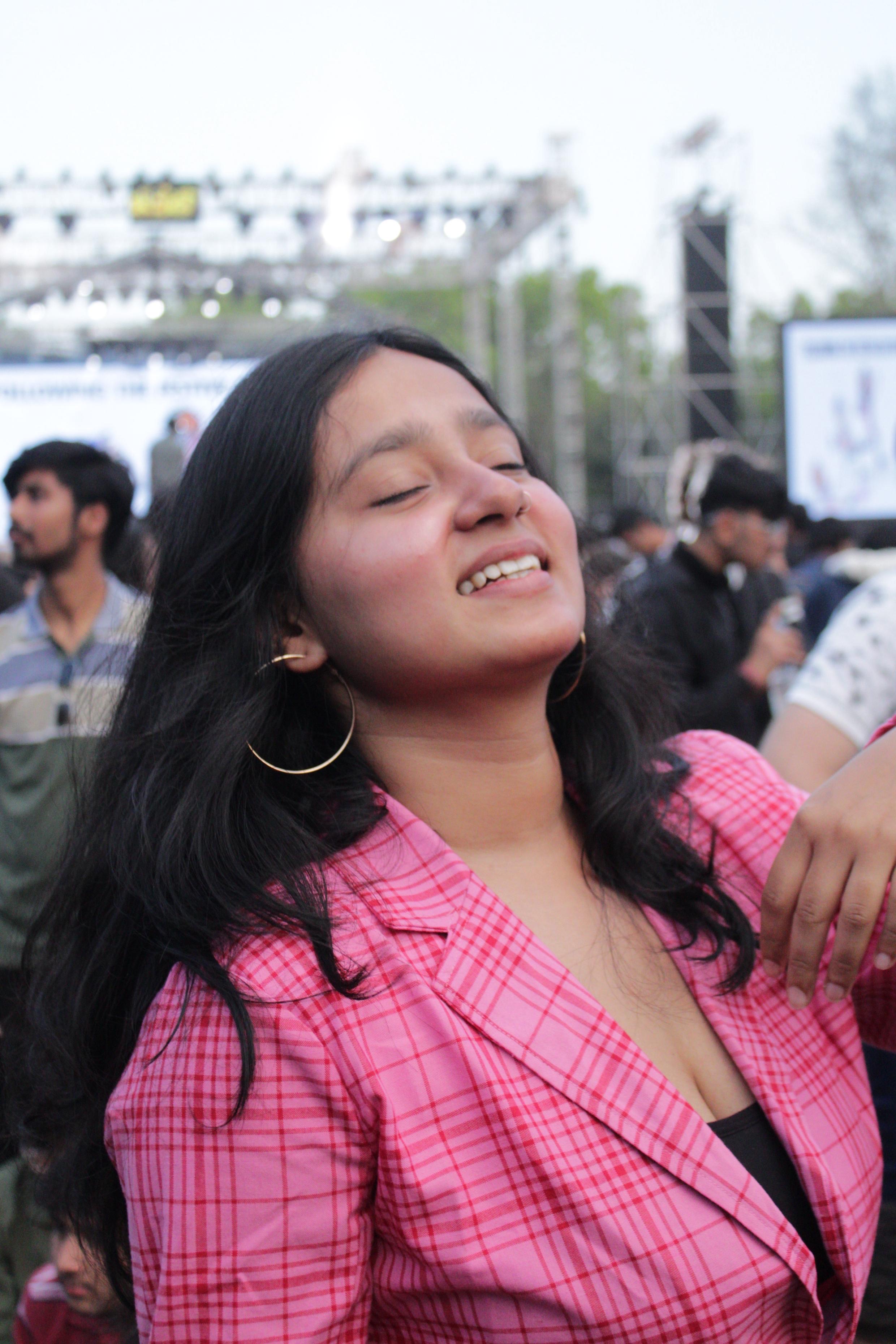 Kanishka Verma smiling confidently in a pink checkered blazer at an outdoor event